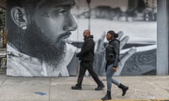 People walk past a mural of American rapper Nipsey Hussle in the Bushwick neighborhood of Brooklyn.