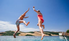 Senior couple jumping into an infinity pool