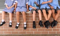 Low section view of five school children sitting on brick wall wearing school uniform