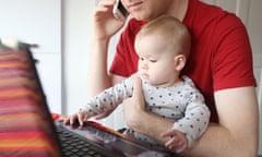 Man working on laptop while holding baby