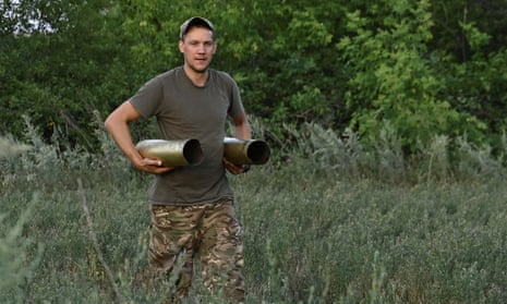 Ukrainian artillerist carries used shells from a self-propelled howitzer after firing towards Russian troops near the town of Chasiv Yar, eastern Ukraine.