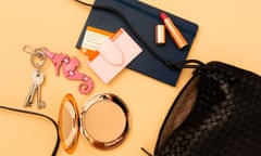 An open handbag with its contents spilling out, including a lipstick, diary, keyring and compact.