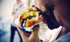 Close-Up Of Man Eating Cheeseburger On Street