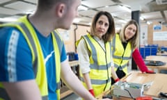 Man and two women at workbench in yellow hi-vis vests