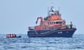 An RNLI boat picks up migrants bound for Dover in an inflatable boat.