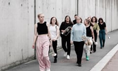 nine women with brass instruments walking down the street