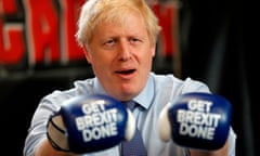 Boris Johnson wears boxing gloves emblazoned with “Get Brexit Done” as he poses for a photograph at Jimmy Egan’s Boxing Academy in Manchester