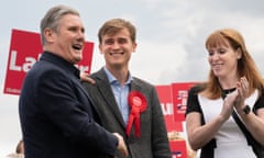 Keir Starmer, Keir Mather and Angela Rayner smile in front of Labour placards
