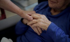 Nurse Leslie Cunich gives resident Norma Buttris’s hand a squeeze after helping her drink in a recreation room at Adina Care, Cootamundra