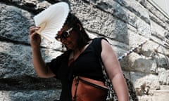 A woman shades herself from the sun as she tries to keep cool along the Brooklyn Bridge in New York during a heatwave in July 2023.