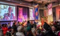 Mourners under colourful drapes with Camila Batmanghelidjh’s image on a screen