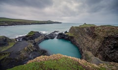 A view from the top of the cliffs across the turquoise lagoon, with glowering clouds in the sky.