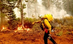 Fire Battalion Chief Craig Newell carries a hose while battling the North Complex fire in Plumas national forest, California, in 2020. 