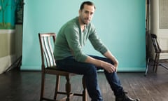 Joseph Fiennes sitting on a chair wearing jumper and jeans