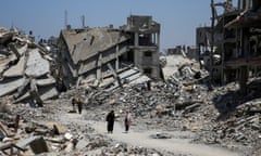 Palestinians walk past houses destroyed during the Israeli military offensive in Khan Younis in the southern Gaza Strip on 10 July.