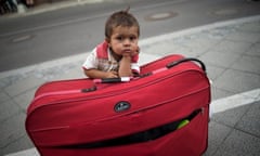 A migrant boy waits at his parents’ suitcase as they  apply for asylum in Berlin