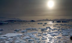 Ice chunks scattered across the North Cove of the Antarctic ocean as a low sun beams fading light over the landscape.