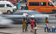 Women talk near a market as cars pass at a roadside market on George W Bush highway in the Tesano neighbourhood