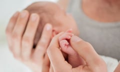 Mother cradling newborn baby’s hand