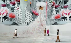 People standing in a room with a large image of a model in a white dress on the wall