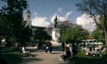 A statue of a man standing in a heroic pose on. aplinth int he middle of a beautiful, leafy Lisbon square