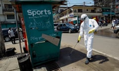 A health worker disinfects a street corner where a suspected Ebola patient was picked up and taken into an ambulance in Monrovia, Liberi