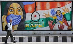 A man walks past a mural showing a scared woman with a hand over her face, hands grabbing another woman, and a noose, with the slogan: 'Real men don't rape!'