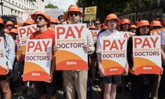 Junior doctors hold orange and white placards reading 'pay restoration for doctors'