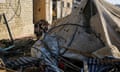 Palestinians sit near a damaged tent