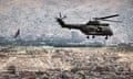 Military helicopter over buildings in the Kabul. Buildings scattered on a mountainside are visible in the background