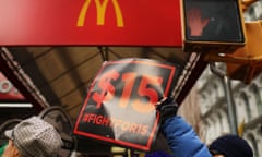 A protester holds a 'fight of $15' sign underneath a McDnald's sign.