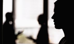 A silhouette of a woman in an office with two co-workers.