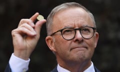 Anthony Albanese holds a one dollar coin