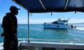 Crew member of Police boat Veiqaravi, watches a pleasure craft motor past in Nadi Bay