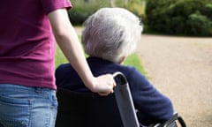 A elderly woman is pushed in a wheelchair