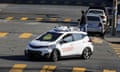 A white self-driving car, with 'Cruise' written on the side, turns in an intersection.