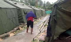 man walks in the rain between tents at a Manus Island regional processing centre for asylum seekers