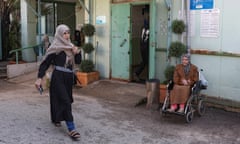 A woman walks past another woman in a wheelchair outside a clinic run by Unrwa at Mar Elias Palestinian refugee camp in Beirut, Lebanon.