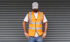 A striker at the Amazon plant in Coventry, wearing cap and hi-vis orange jacket, looking down