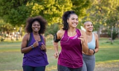 A group of women jogging together on a sunny day in a park.