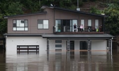 People look out at the swollen Hawkesbury River from the deck of a partially submerged house as floodwaters rise in western Sydney, in western Sydney Tuesday, March 23, 2021 Thousands of residents are fleeing their homes, schools are shut, and scores of people have been rescued as NSW is hit by once-in-a-generation flooding. (AAP Image/Pool,Loren Elliott ) NO ARCHIVING