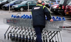 Tesco employee pushing trollies in carpark