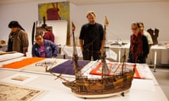 A moel ship is examined by people in a museum