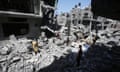 Adults and children stand and walk on concrete rubble from a collapsed building