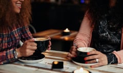 Cropped shot of two women sitting at restaurant holding cup of coffee. Female friends drinking coffee at a table<br>F1TBE7 Cropped shot of two women sitting at restaurant holding cup of coffee. Female friends drinking coffee at a table