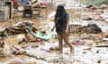 A resident walks among debris of destroyed belongings next to her house at a village in Manila