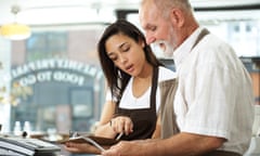 An older man and young woman working together in a cafe