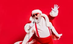 Man dressed as Santa, wearing dark sunglasses and singing enthusiastically into a microphone