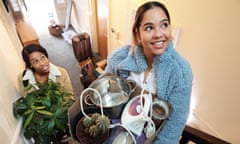 Two women moving in to apartment carrying a box of possessions and household objects upstairs