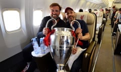 Jürgen Klopp holds the Champions League trophy with Mike Gordon, the FSG president, on the plane back from the 2019 final win in Madrid